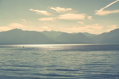 Scenic view of sea by mountains against sky