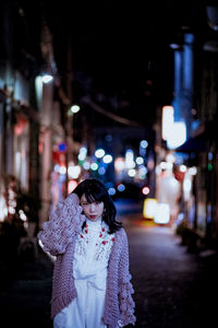 Young woman on illuminated street at night