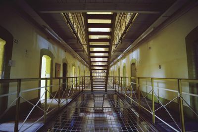 Illuminated interior of a prison building with open doors facing corridor and a staircase