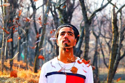  young man looking up at leaves falling in forest