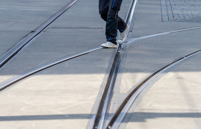 Low section of person walking on road with railroad track