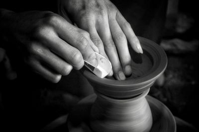 Cropped hands shaping pottery in darkroom