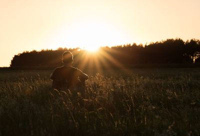 Man sitting on a field watching the sunset