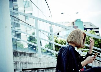 Woman using mobile phone while standing on railing