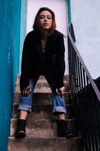 Portrait of young woman standing against stairs