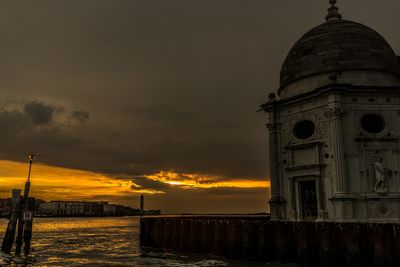 View of building by sea against sky during sunset