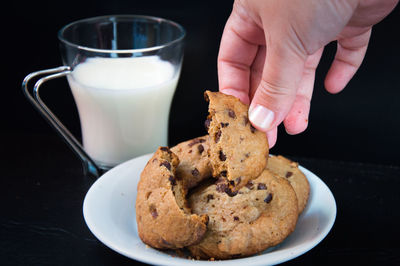 Cropped hand having cookies against black background