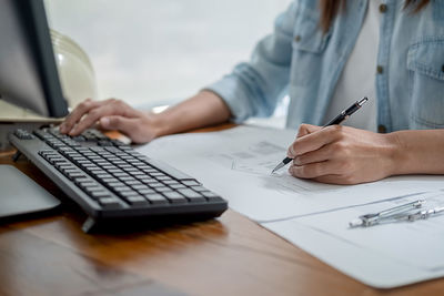 Midsection of woman using mobile phone on table