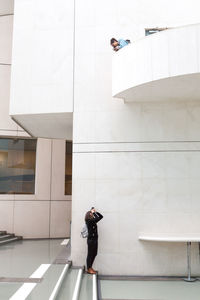Full length of young woman photographing in city