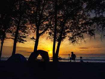 Silhouette people on beach against sky during sunset