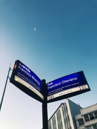 Low angle view of road sign against clear blue sky