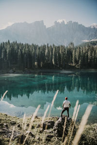 Man standing on rock at carezza lake in south tyrol, italy