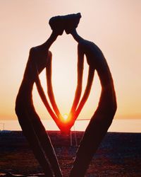 Silhouette heart shape on beach against sky during sunset