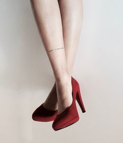 Close-up of legs wearing high heels over white background