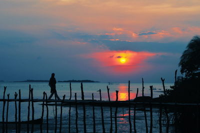 Silhouette people by sea against sky during sunset