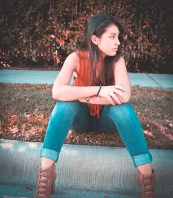 Young woman looking away while sitting outdoors