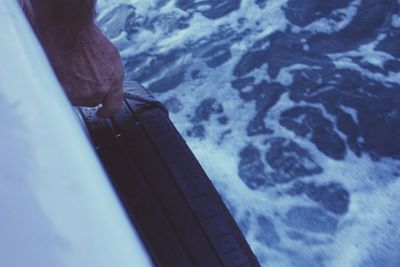 Cropped hand holding tire on boat sailing in sea