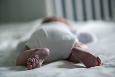 Close-up of newborn sleeping on bed at home