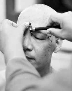 Cropped hand of person shaving men head