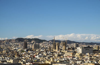 Distant view of sagrada familia in city against sky