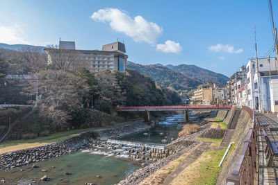Bridge over canal by buildings in city against sky