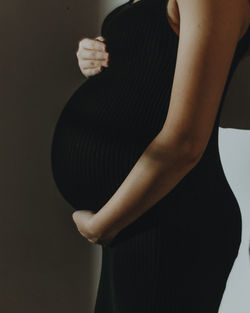 Midsection of woman standing against gray background