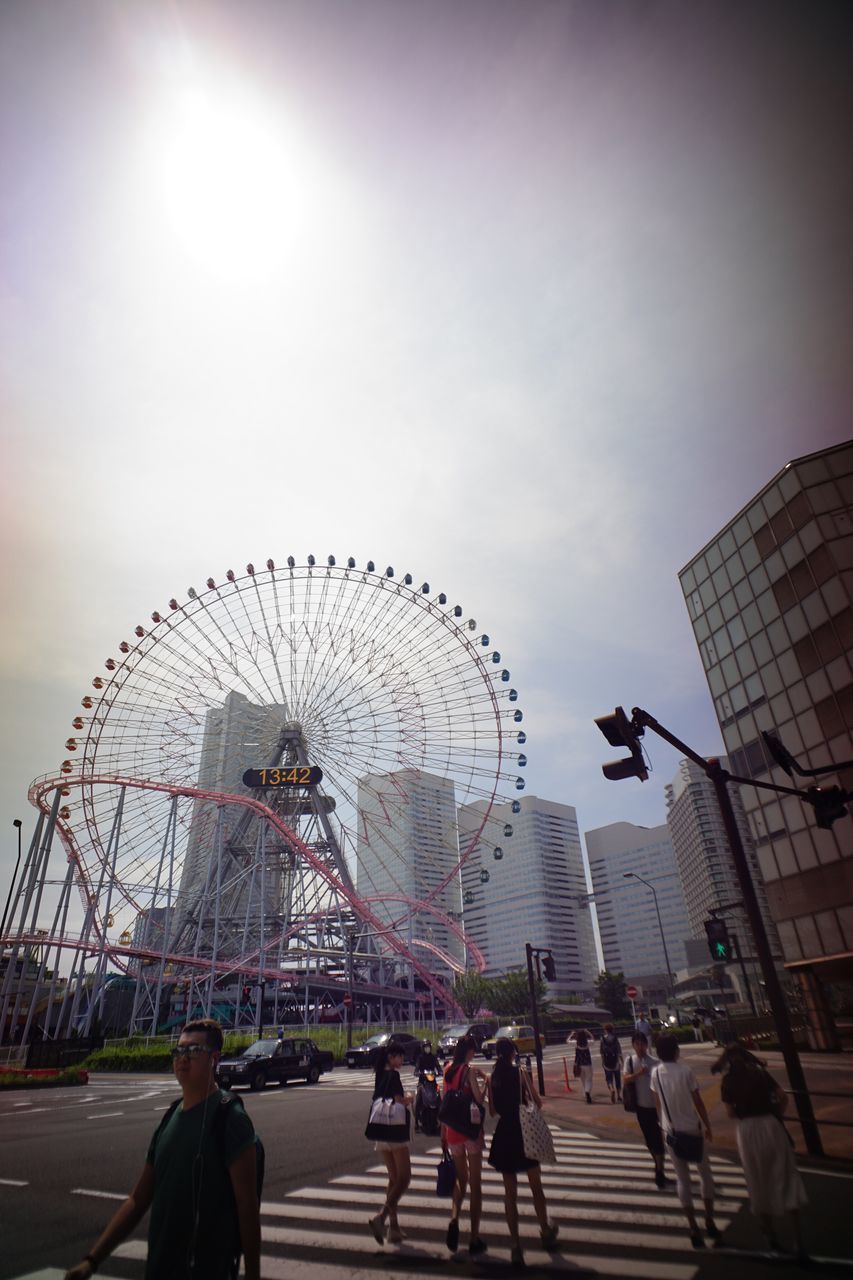 ferris wheel, amusement park, amusement park ride, arts culture and entertainment, architecture, built structure, leisure activity, sky, lifestyles, city, enjoyment, fun, travel destinations, city life, tourism, capital cities, outdoors, group of people, mixed age range, modern, chain swing ride, day, cloud - sky