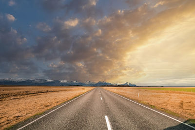 Empty diminishing road amidst volcanic landscape against sky during sunset