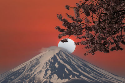 Scenic view of snow covered mountain against orange sky