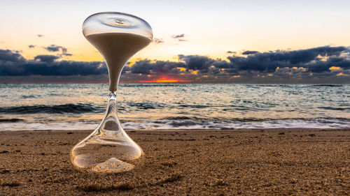 Umbrella on beach against sky during sunset