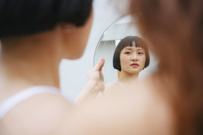 Reflection of lesbian sisters holding mirror outdoors