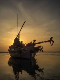 Silhouette ship in sea against sky during sunset