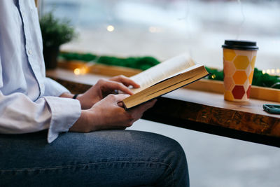 Brunette girl in a cafe drinking coffee, reading a book