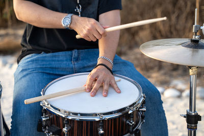 Midsection of man playing drum