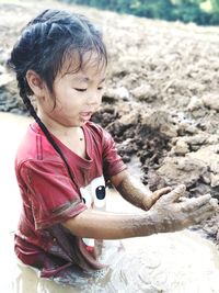 Girl playing with mud in puddle
