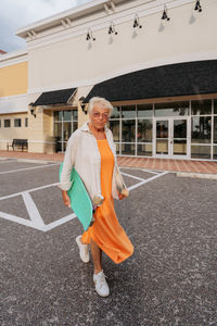 Portrait of elderly women in orange dress holding skateboard