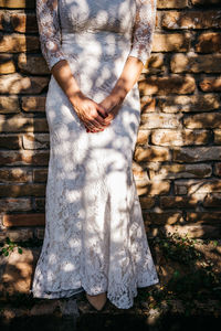 Midsection of woman standing against brick wall