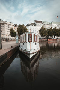 Boats in river by buildings in city against sky