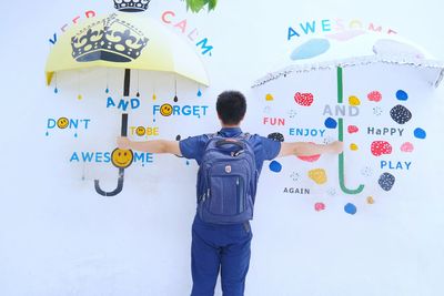 Optical illusion of man holding umbrellas with graffiti against wall