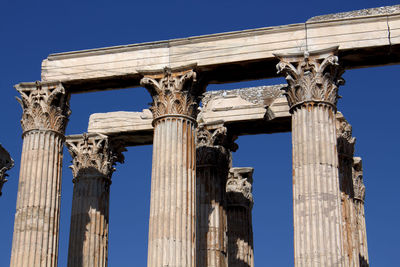 Low angle view of historic columns against blue sky