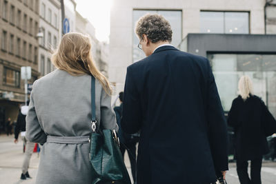 Rear view of female business person with male coworker in city