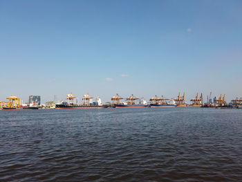 Sea by commercial dock against clear sky