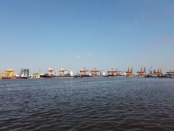 Sea by commercial dock against clear sky