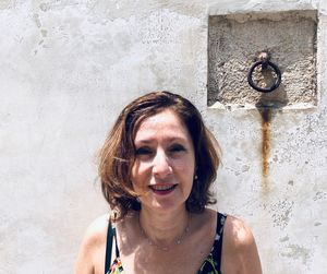 Portrait of mature woman smiling against wall