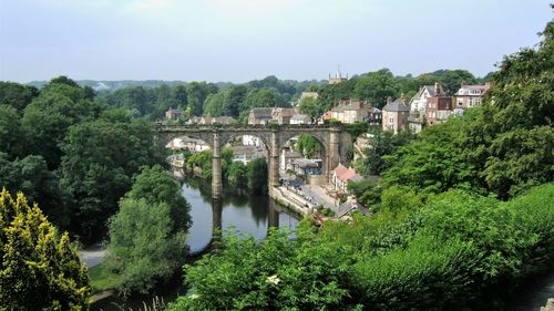 Viaduct over river in city against sky