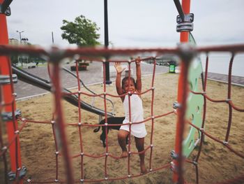 Full length of girl climbing on jungle gym in playground