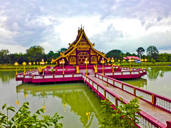 View of temple at lake against cloudy sky