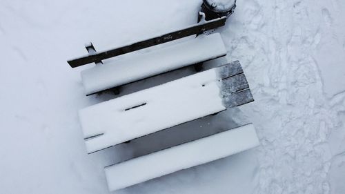 High angle view of snow covered bench on field