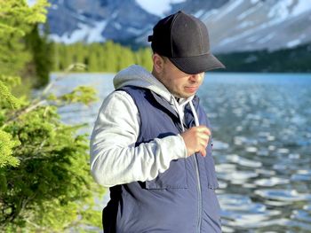 Man wearing hat standing against water