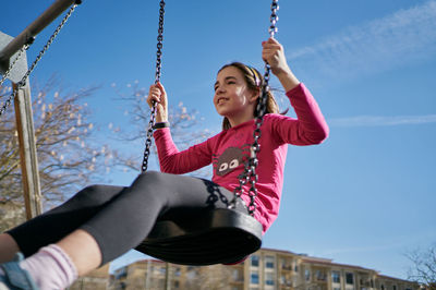 Girl on a swing with a blue sky background